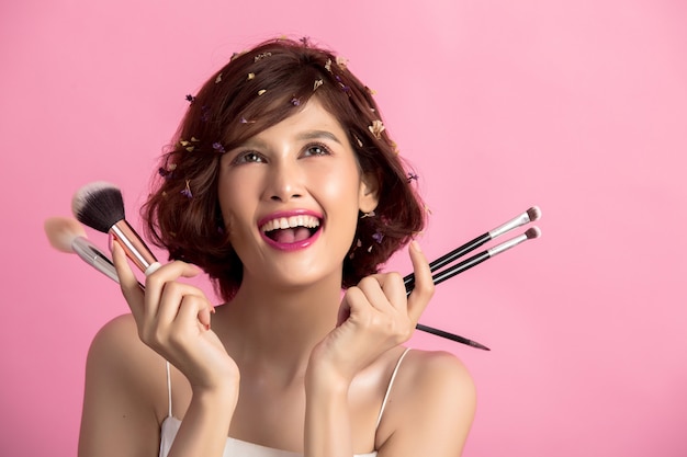 Short hair asian young beautiful woman applying cosmetic powder brush 