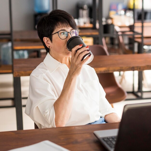 コーヒーを飲む短い髪のビジネス女性