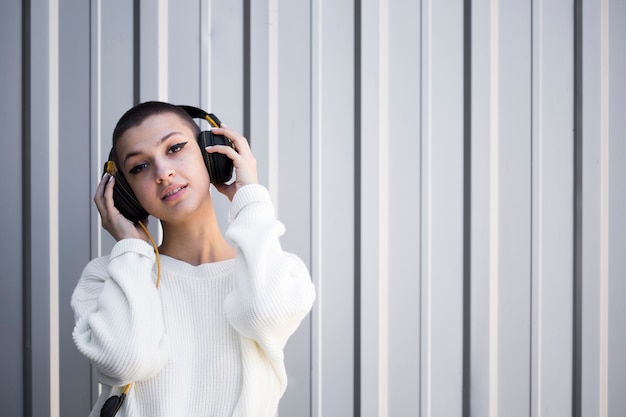 Short-haired teenager listening to music with headphones