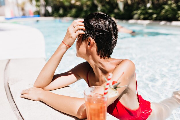 Foto gratuita donna dai capelli corti che guarda lontano mentre nuota in una giornata calda.