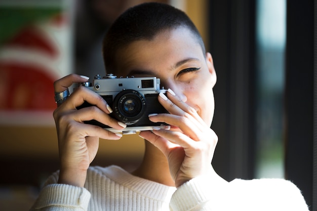 Short-haired woman taking photo with vintage camera