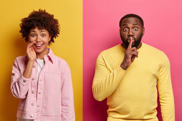 Кадр: афроамериканка хихикает над забавной шуткой, удивленный бородатый мужчина делает жест молчания, рассказывает секретную информацию