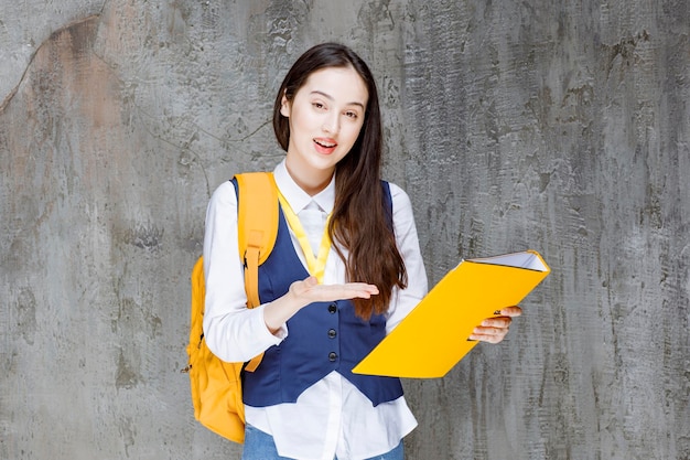 Shot of beautiful girl with yellow folder standing. High quality photo