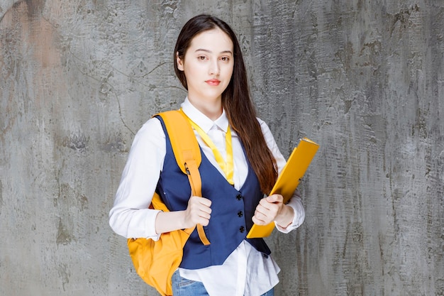 Free photo shot of beautiful girl with yellow folder standing and posing. high quality photo