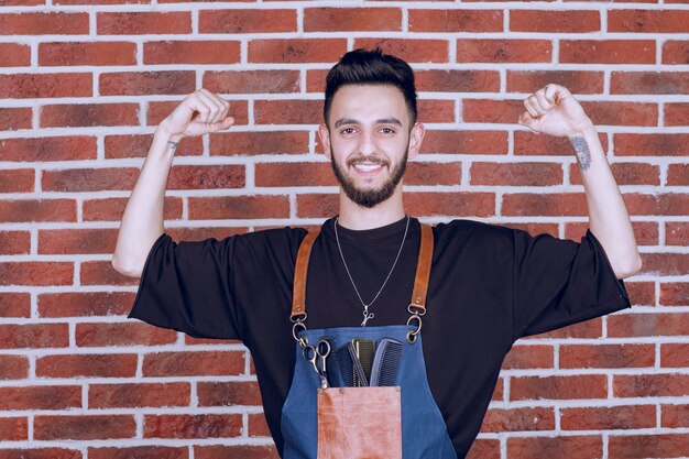 Shot of brunette hairdresser showing his muscle. High quality photo