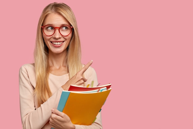 shot of cheerful satisfied female model with toothy smile, wears transparent glasses