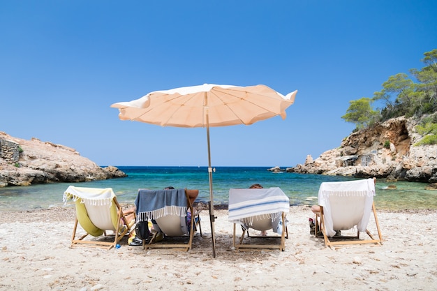 Shot of four  people in sunbeds on the beach