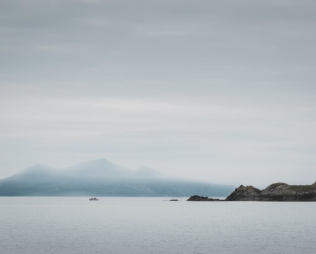 Shot of a lake and cliffs, misty mountains