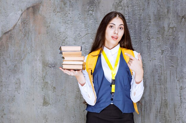 Shot of long haired female student with books standing. High quality photo