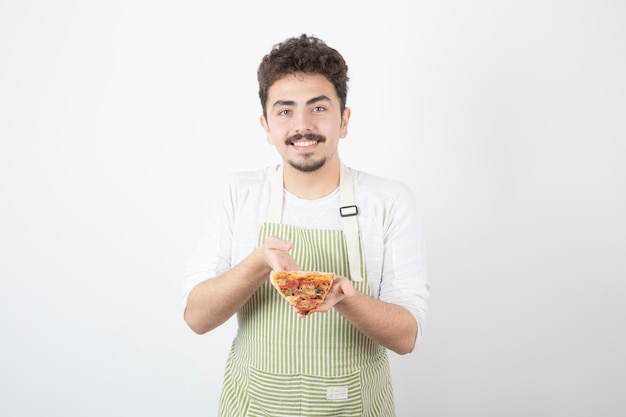 Shot of male cook holding slice of pizza on white 