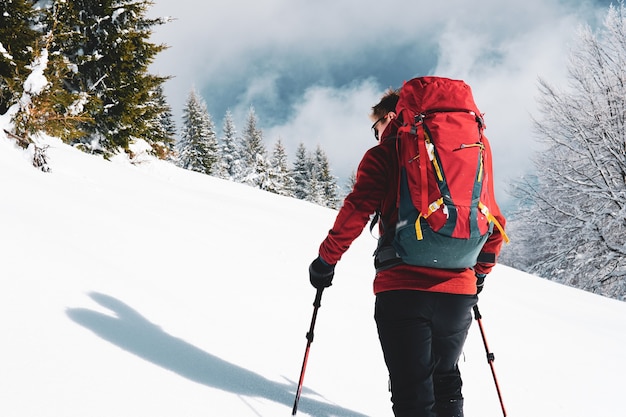 За кадром человека, занимающегося ски-альпинизмом в заснеженных горах