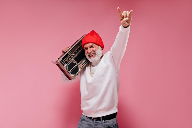 Shot of man in White sweater smiling and holding record player Cheerful adult guy in stylish clothes posing on isolated background