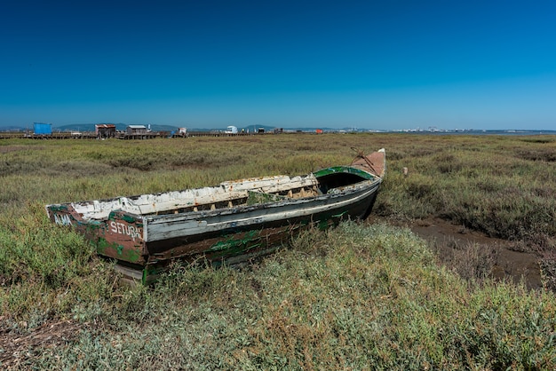 Shot of an old boat in the middle of a meadow in Cais Palafítico da Carrasqueira, Portugal