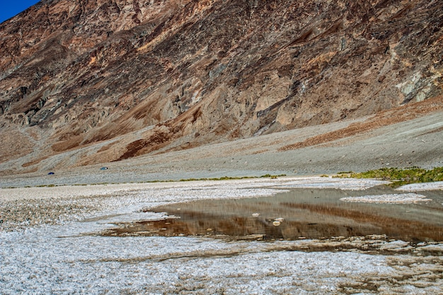 Shot of partially dried puddle ahead of the rocky foothill