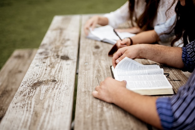 снимок людей, сидящих рядом и читающих Библию