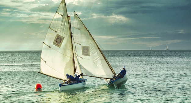Снимок людей на белых лодках, плавающих в море в пасмурную погоду