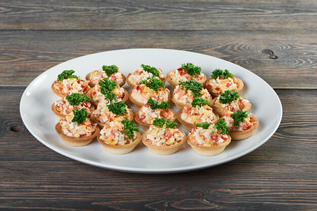 Shot of a plate with tartlets with salad decorated with greens on the wooden table appetizer gourmet luxury living restaurant menu food order delicious tasty eating.