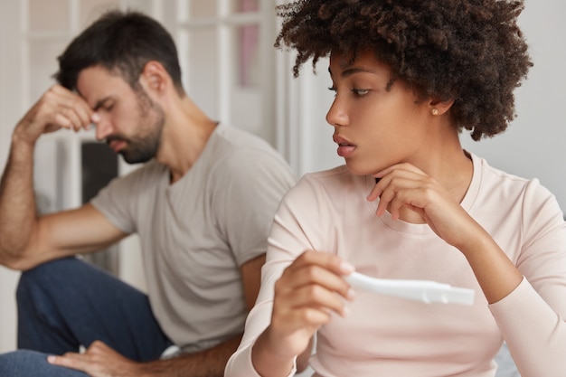 Shot of pleasant looking black woman holds pregnancy test with negative result