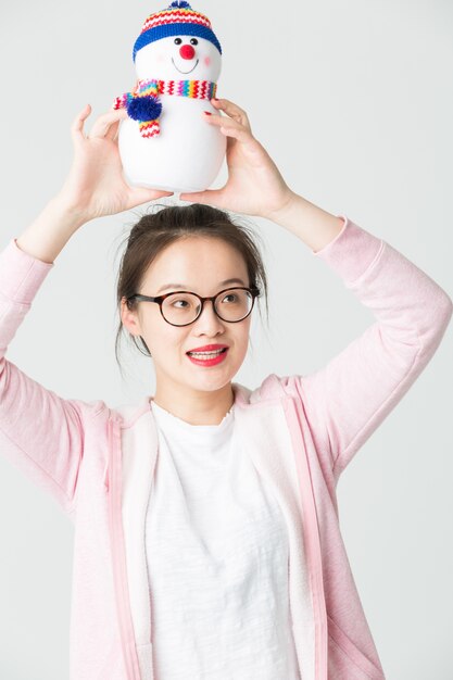 Shot in the studio of the young asian woman holding a Christmas Snowman