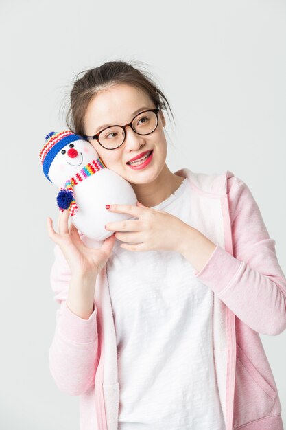 Shot in the studio of the young asian woman holding a Christmas Snowman