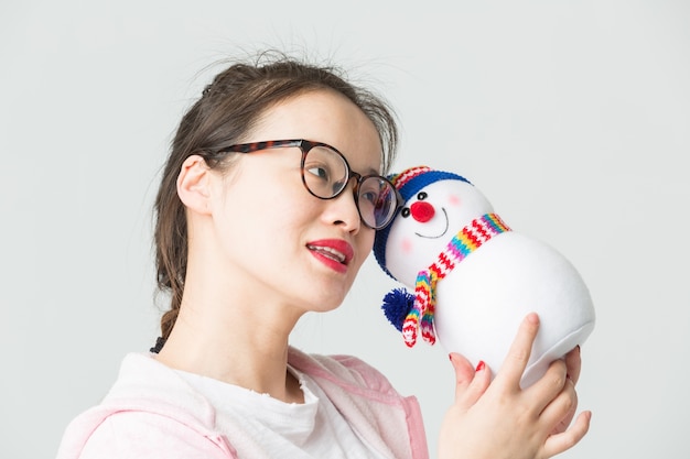 Shot in the studio of the young asian woman holding a Christmas Snowman