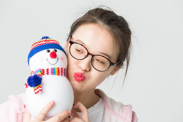 Colpo in studio della giovane donna asiatica con un pupazzo di neve di natale