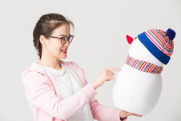 Shot in the studio of the young asian woman holding a Christmas Snowman