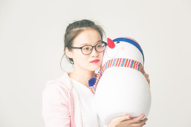 Shot in the studio of the young asian woman holding a Christmas Snowman