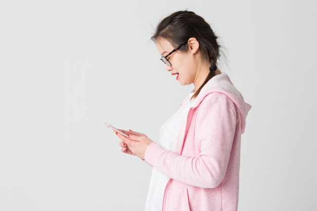 Shot in the studio of the young asian woman playing mobile phone