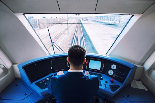 Foto gratuita colpo dell'interno della cabina di pilotaggio del treno con conducente seduto e guida del treno