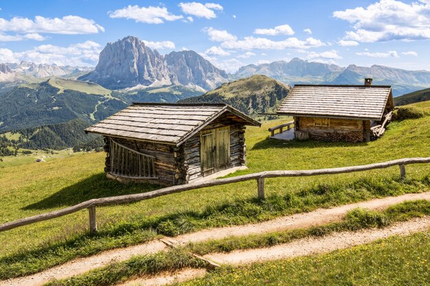 Shot of two wooden cabins on a meadow with the mountains in the background