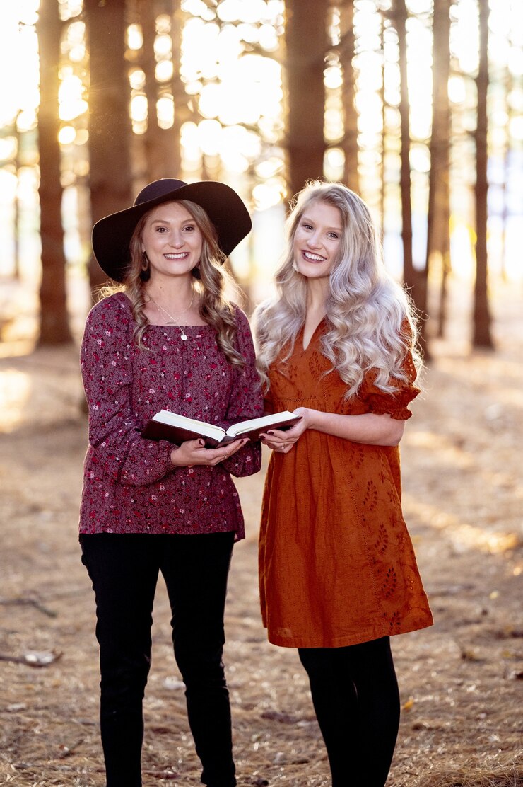 Free Photo shot of two young females posing with a book in the forest, autumn mood