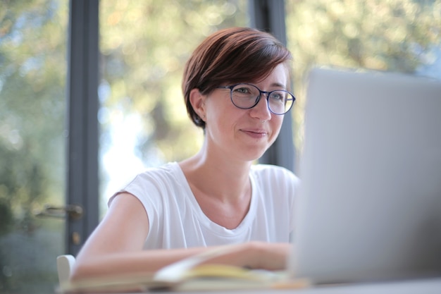 Colpo di una donna con gli occhiali che lavora sul suo laptop