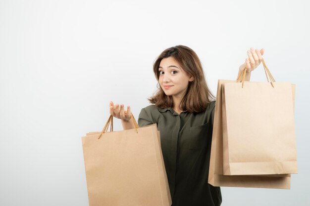 白の上に立っているクラフトバッグを持つ若い女性モデルのショット。高品質の写真