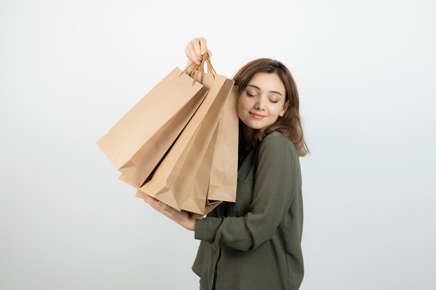 白の上に立っているクラフトバッグを持つ若い女性モデルのショット。高品質の写真
