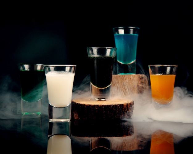 Shots in glasses of different colors against the background of smoke