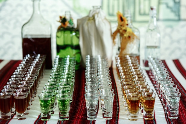 Shots with different colored drinks stand on embroidered table