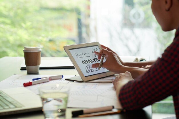 Over the shoukder view of unrecognizable person examining analysis chart on tablet PC