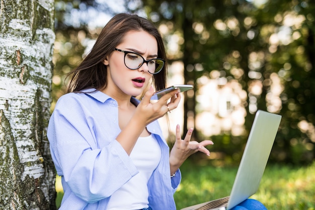 Shouting girl in blue jeans work with laptop in citypark