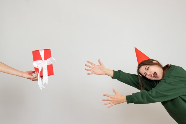 shouting girl with party cap trying to catch gift in human hand on white