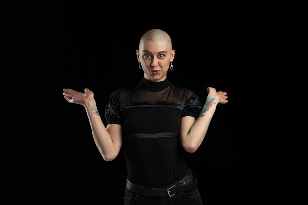 Showing, cute. Monochrome portrait of young caucasian bald woman isolated on black wall.