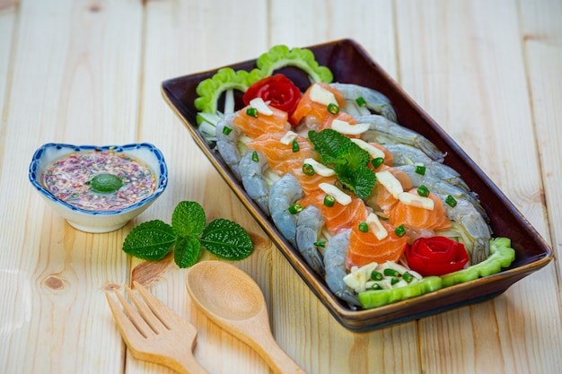 Бесплатное фото Острый салат из креветок и лосося на деревянной поверхности