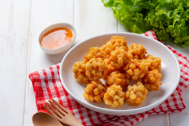 Palline di gamberetti ricoperte di fritto impanato sulla superficie in legno bianco.