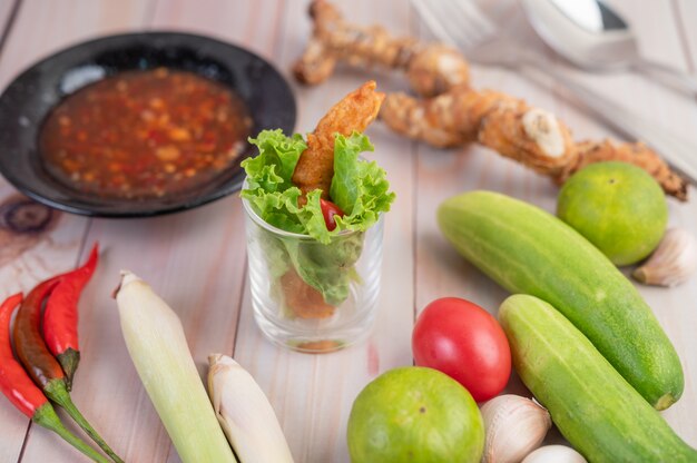 Shrimp deep fried batter placed on salad and tomatoes in a wooden bowl.