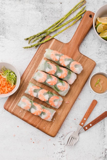 Free photo shrimp rolls on chopping board with asparagus