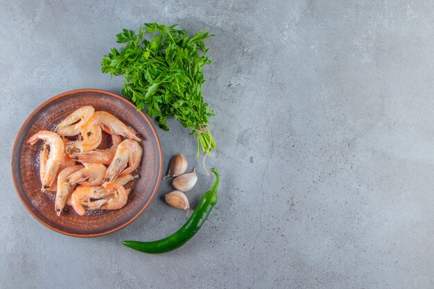 Free photo shrimps on a plate next to parsley bunch , on the marble background.