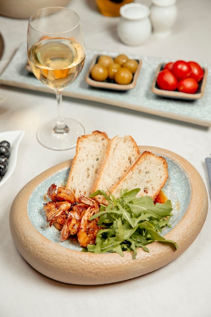 Free photo shrimps with arugula and bread served with white wine