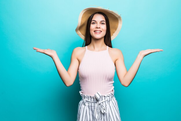 Shrugging woman in doubt doing shrug showing open palms, gesturing, look to side isolated on blue wall.