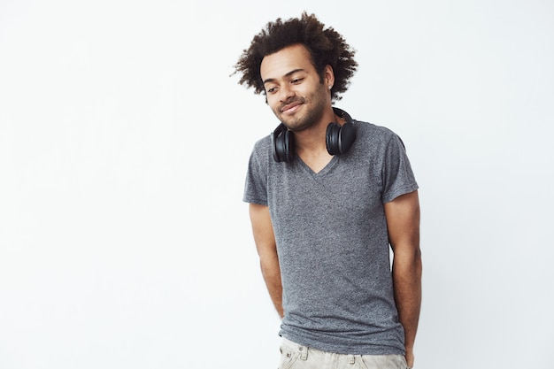 Shy african man with headphones smiling looking down.