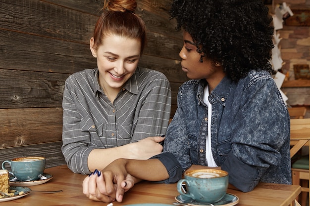 Shy beautiful redhead woman with hair bun smiling joyfully sitting at coffee shop